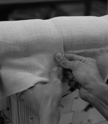 Chester’s founder examining a sheet of leather inside the workshop, surrounded by materials used to create the brand’s handcrafted furniture.