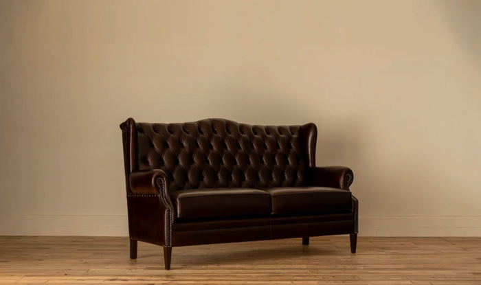 45-degree angle: Angled view of theJames Chesterfield 3-Seater Sofa in deep brown leather with diamond button tufting, rolled wingback arms, and nailhead trim, on tapered wood legs.