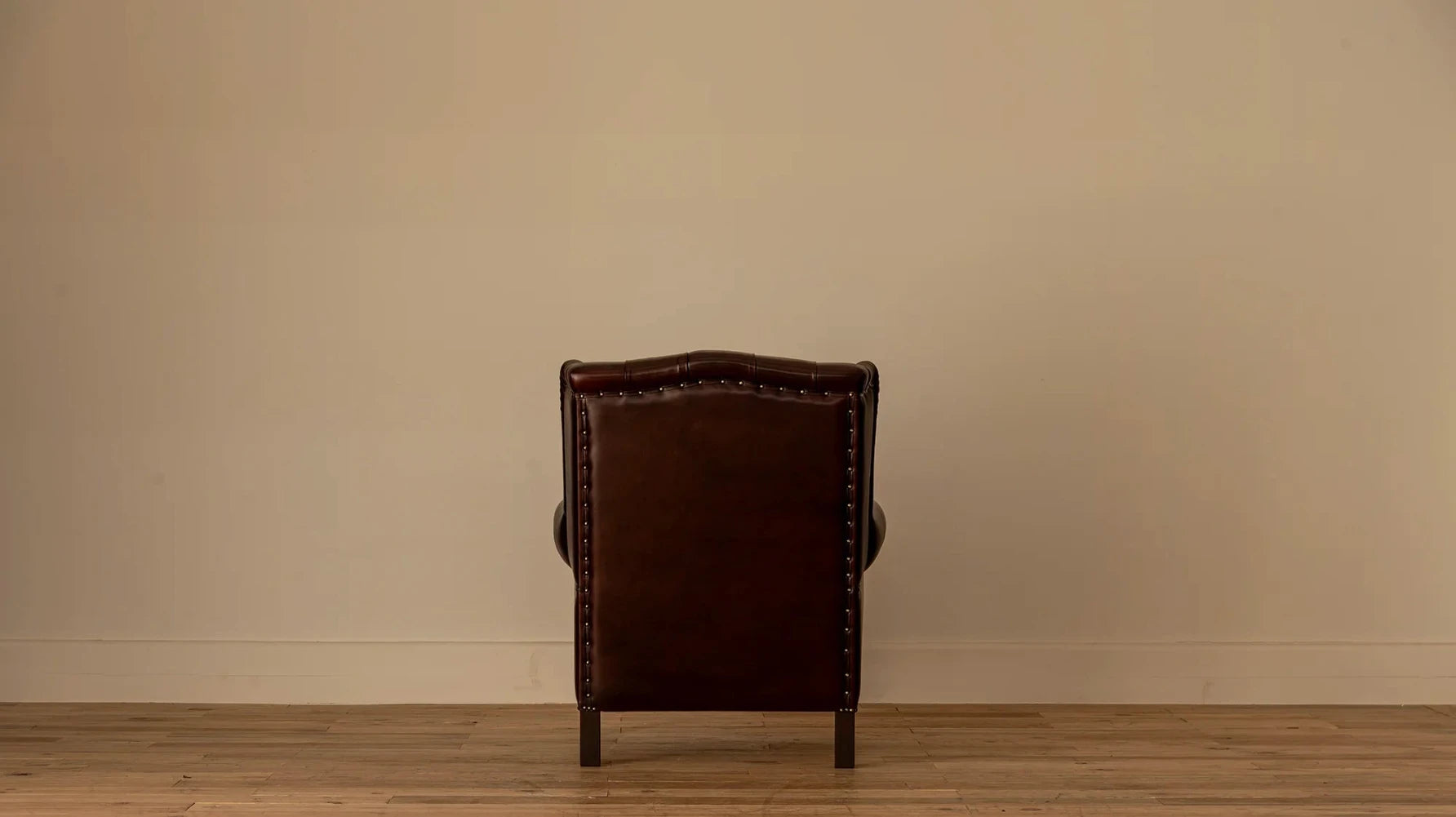Back view: Rear view of the James Chesterfield armchair showing the panelled leather back with nailhead trim along the edges.