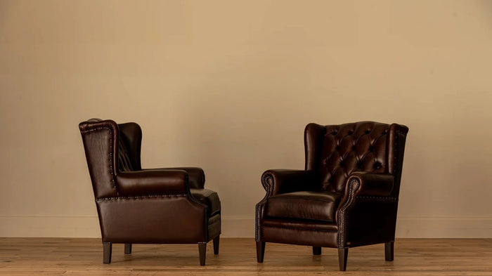 Pair, side view: "Two James Chesterfield wingback armchairs facing each other, showing matching tufted backs and nailhead trim