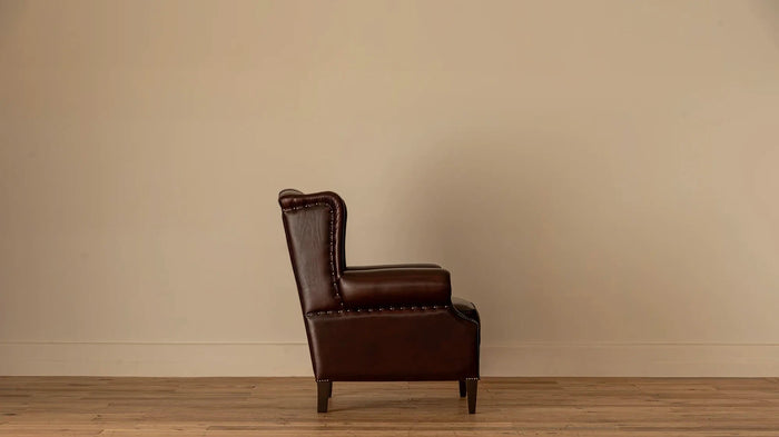 Side view: "Side profile of the James Chesterfield wingback armchair showing its high tufted back, rolled arm, and nailhead trim