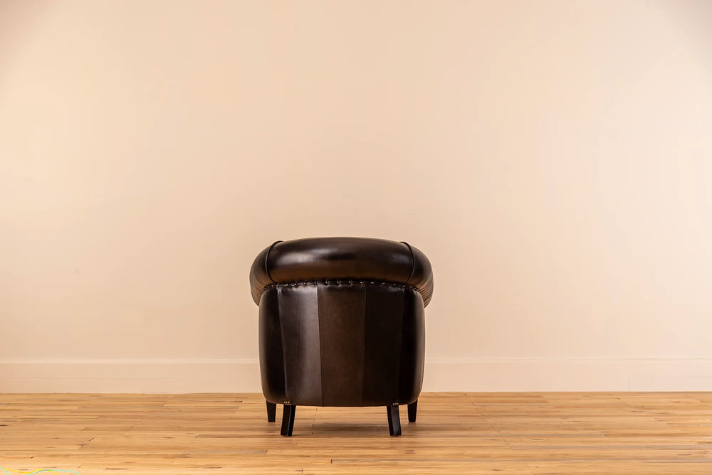 Black leather armchair against a beige wall on a wooden floor