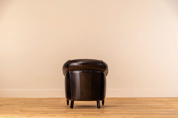 Black leather armchair against a beige wall on a wooden floor