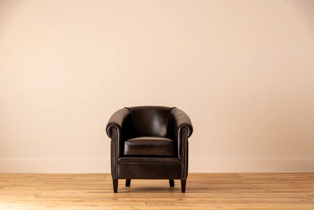 Black leather armchair in a room with a beige wall and wooden floor.