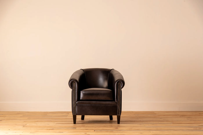 Black leather armchair in a room with a beige wall and wooden floor.