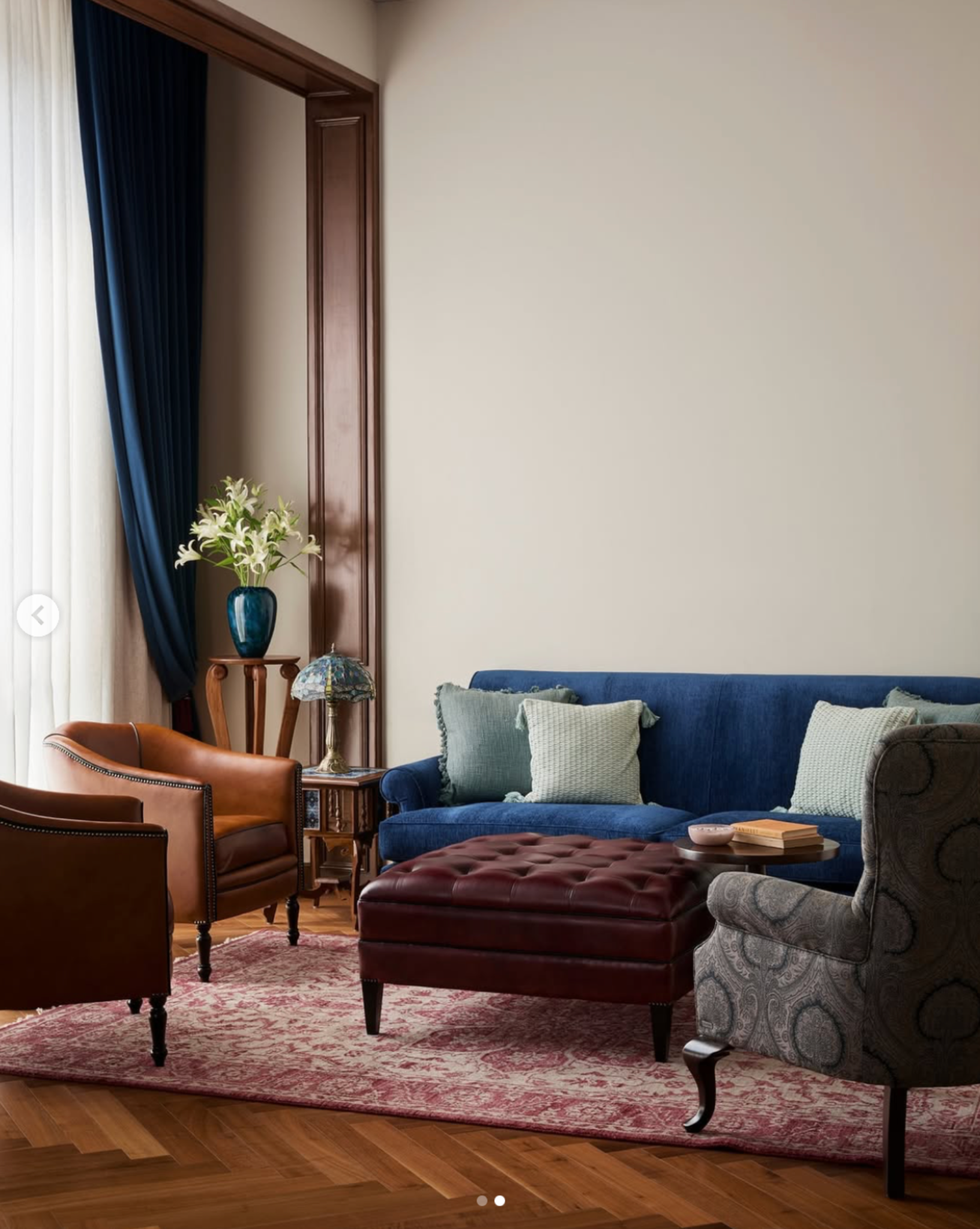 Living room with a blue sofa, leather armchairs and a burgundy tufted ottoman.