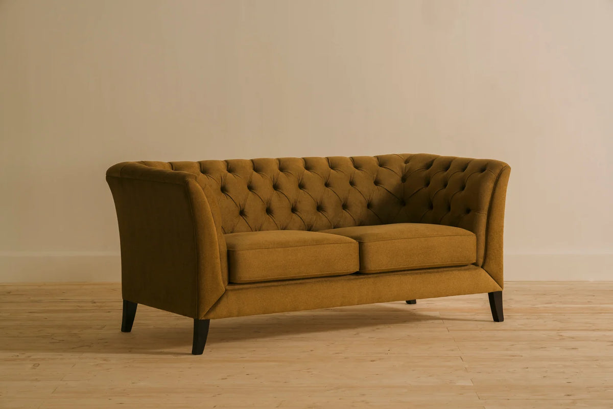 Chelsea 2-seater chesterfield sofa in mustard fabric upholstery with deep button tufting and slender rolled arms. Handcrafted by Chester's India with a solid wood frame for a refined, contemporary take on the classic Chesterfield.
