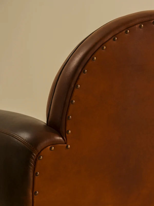 Close-up view of the Madame Armchair by Chester's India, showcasing its curved club silhouette in Shadow Red Brown full grain leather.